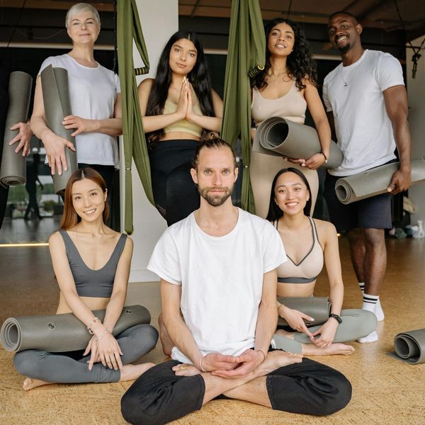 A diverse group of expectant mothers smiling and sitting on yoga mats.