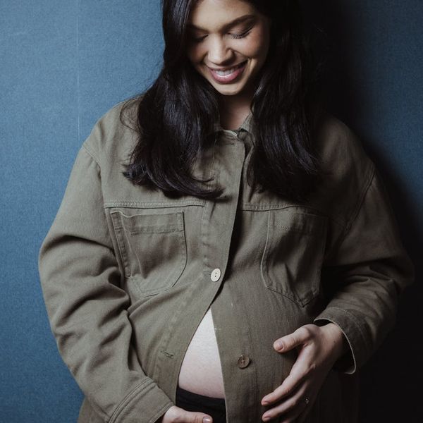 Profile of a pregnant woman meditating peacefully with her hands on her belly.